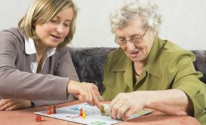 Carer playing board game with elderly lady